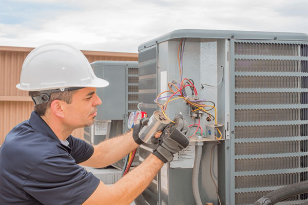 young HVAC worker repairing wires on an ac unit outdoors